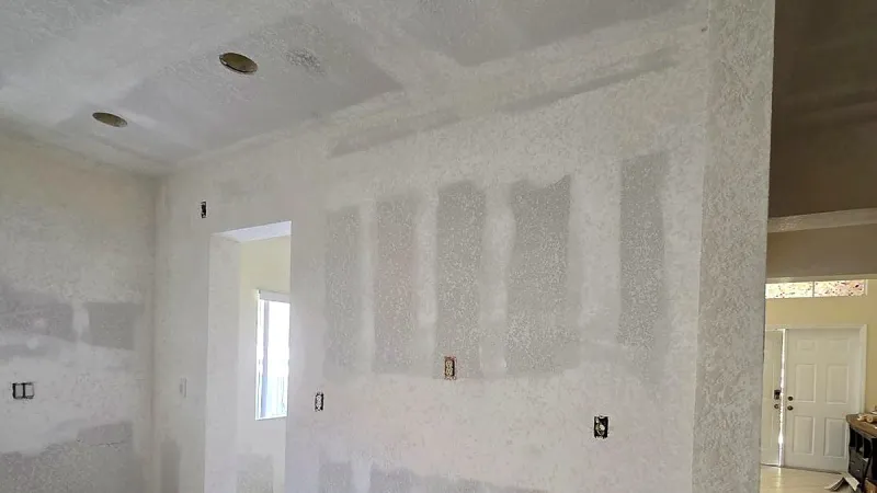 Bright room with patched drywall and joint compound on the wall and ceiling