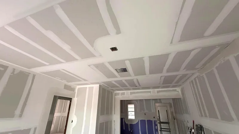 Drywall taping in progress on a coffered ceiling