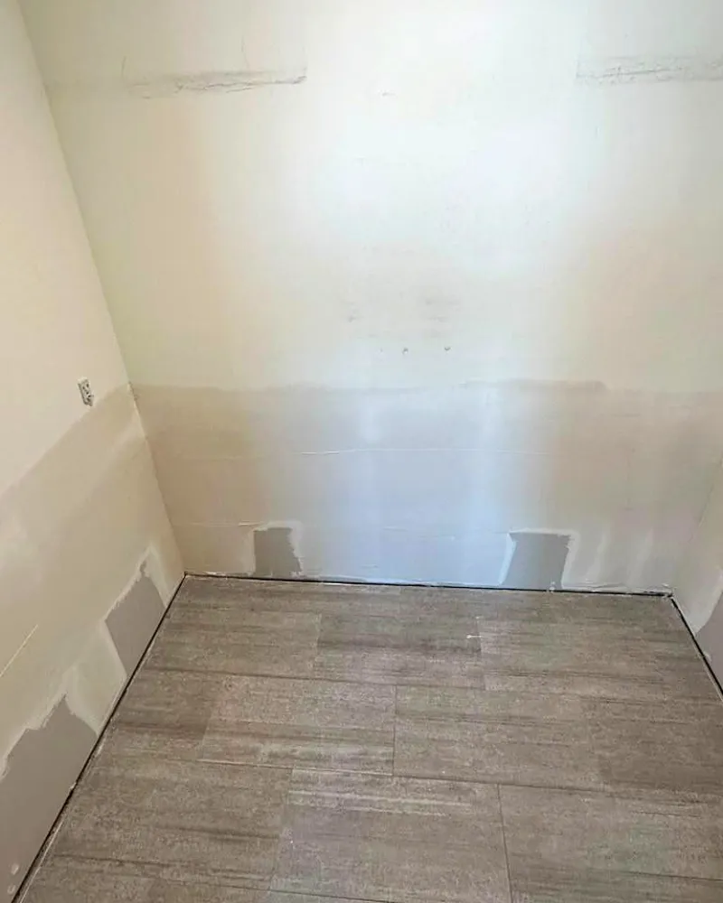 New tile floor installed beside freshly patched walls