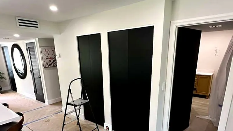 Finished room with white walls, black doors and a stepladder on a protected floor