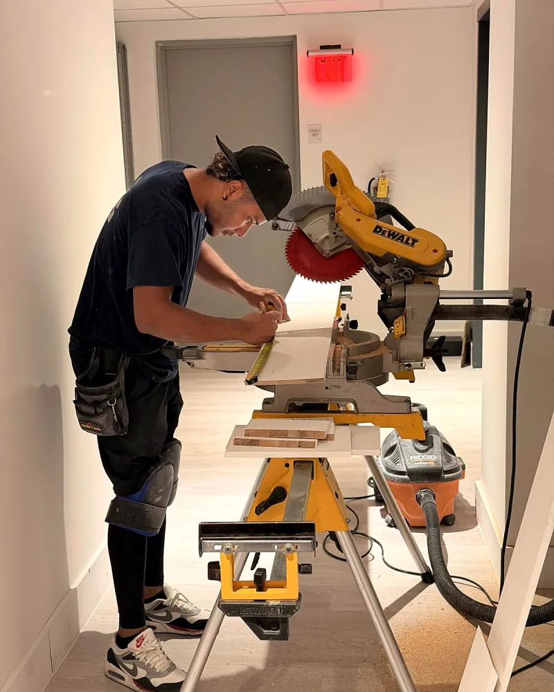 Crew member measuring trim at a miter saw