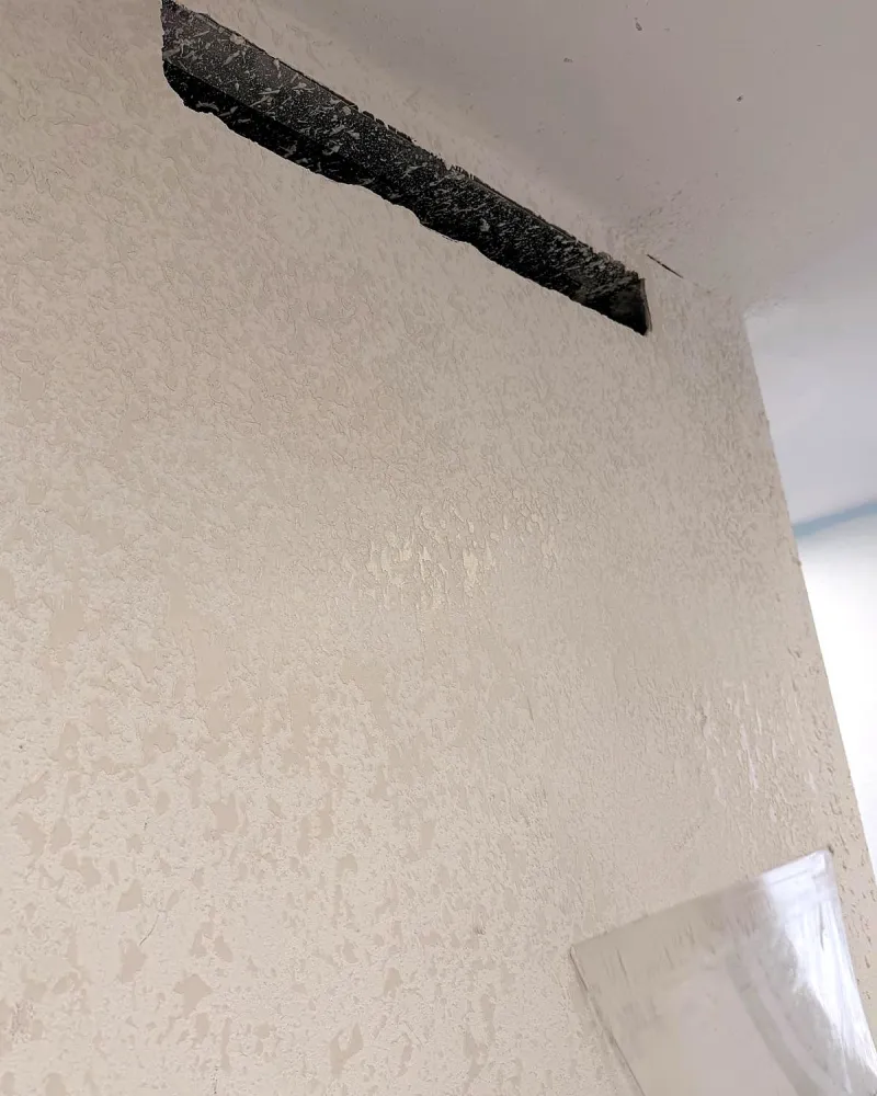 Popcorn textured wall and ceiling edge before removal